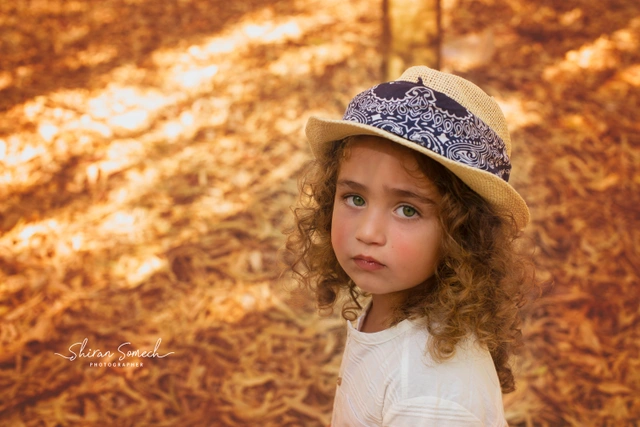 ילדה עם כובע קש ובנדנה מביטה למצלמה
