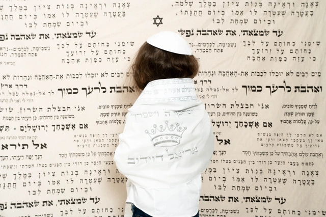 ילד עם כיפה לבנה בחולצה רקומה וכתובה