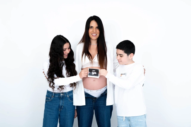 אישה בהריון עם שני ילדים מחזיקים תמונת אולטרסאונד