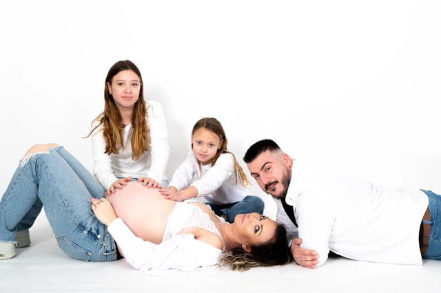 דיוקן משפחתי בסטודיו עם הורים ושני ילדים סביב בטן של אם הרה.