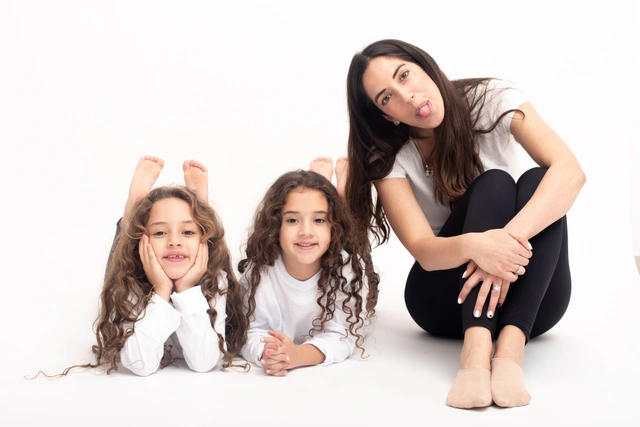 אם ושתי בנותיה מחייכות ומצחקקות בסטודיו.