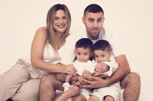 משפחה של חמישה מחייכת למצלמה, כולל אמא, אבא, שני בנים קטנים ותינוק שרק נולד.