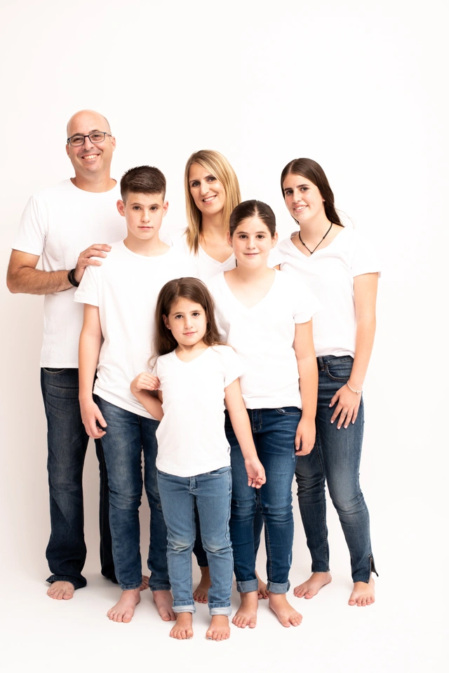 משפחה בת שש נפשות מחייכת ומצטלמת יחד בסטודיו.