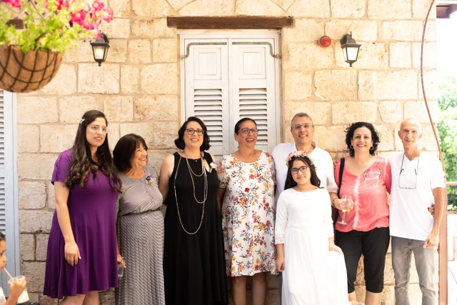 משפחה של שמונה מבוגרים וילדים עומדים בחיוך בחוץ.